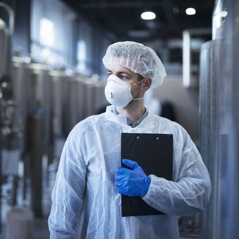 technologist-in-protective-white-suit-with-hairnet-and-mask-standing-in-food-factory-1536x1025.jpg